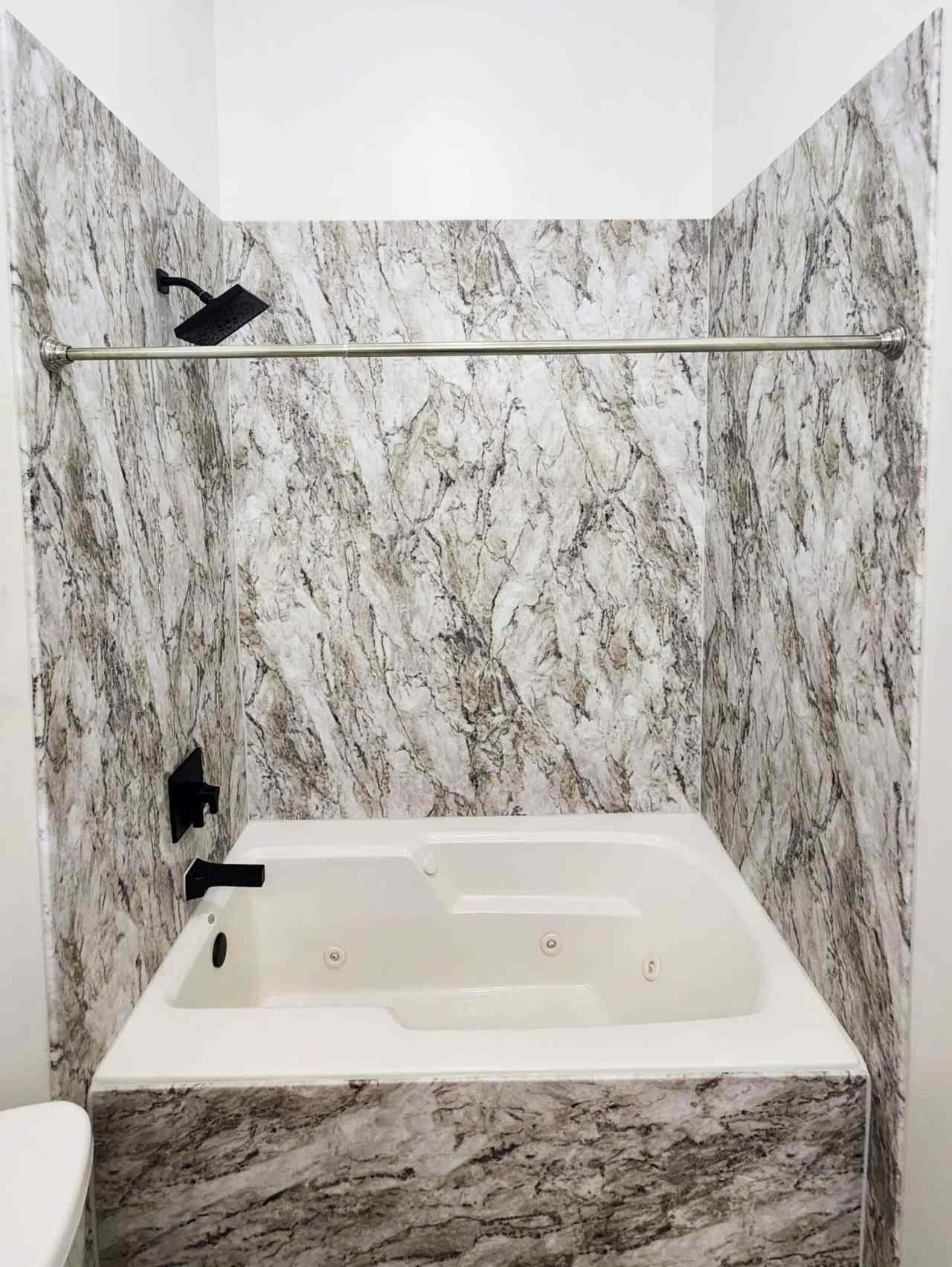 98f3c20a-3c8f-44a3-81d9-6faa1490c3c0 marble shower with white bathtub and black fixtures