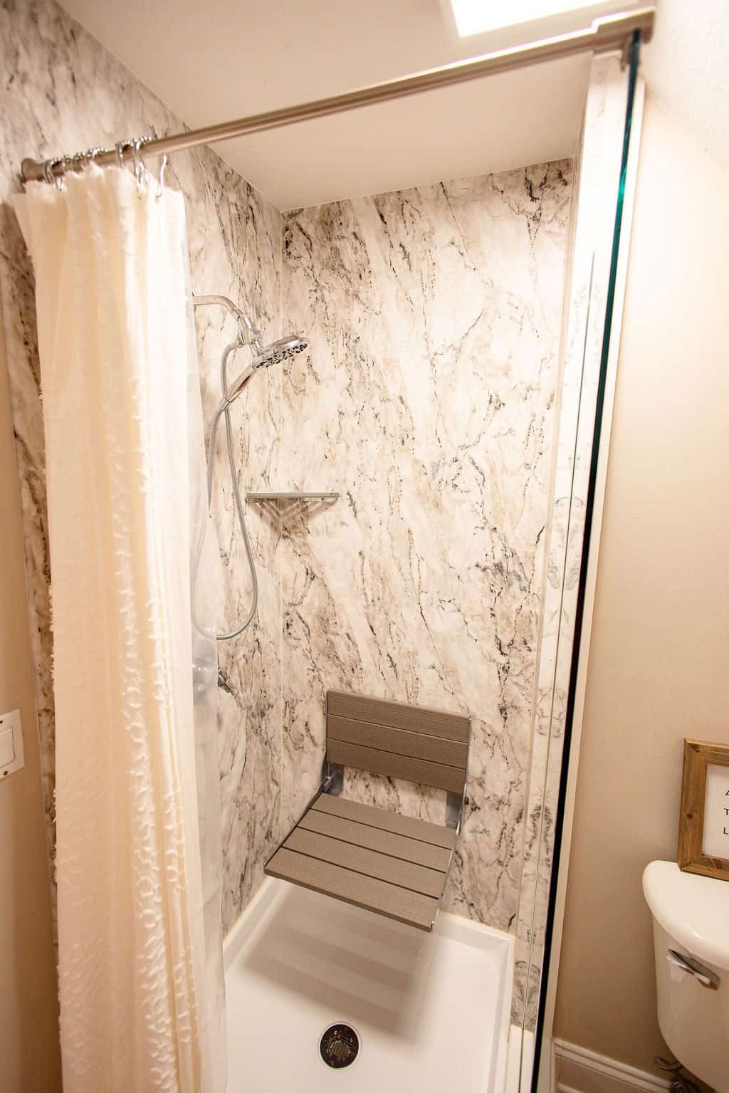 marble shower with folding bench and nickel fixtures