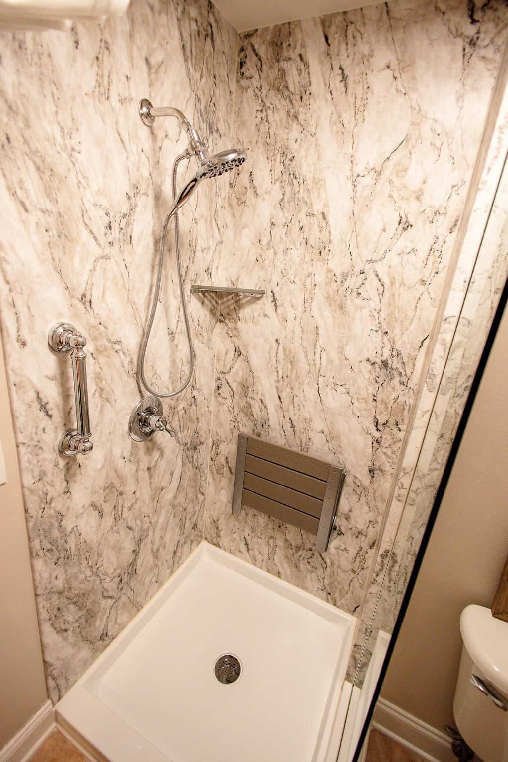 LatashaCarrawayPhotography-3336 closeup of marble shower with grab bar, corner caddy, and folding bench seat