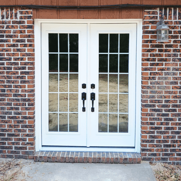 cropped image of red brick home with white french patio doors