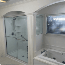 Shower and bathtub bathroom upgrade with modern glass shower enclosure and new window in a residential setting.