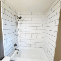 Modern white tiled bathroom with showerhead, showcasing high-quality bathroom remodeling and renovation services offered by HTC Pros in NWFL.