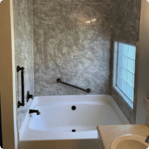 Modern bathroom with a soaking tub, textured wall finishes, and a large window providing natural light, showcasing home renovation and bathroom remodeling services by HTC Pros.