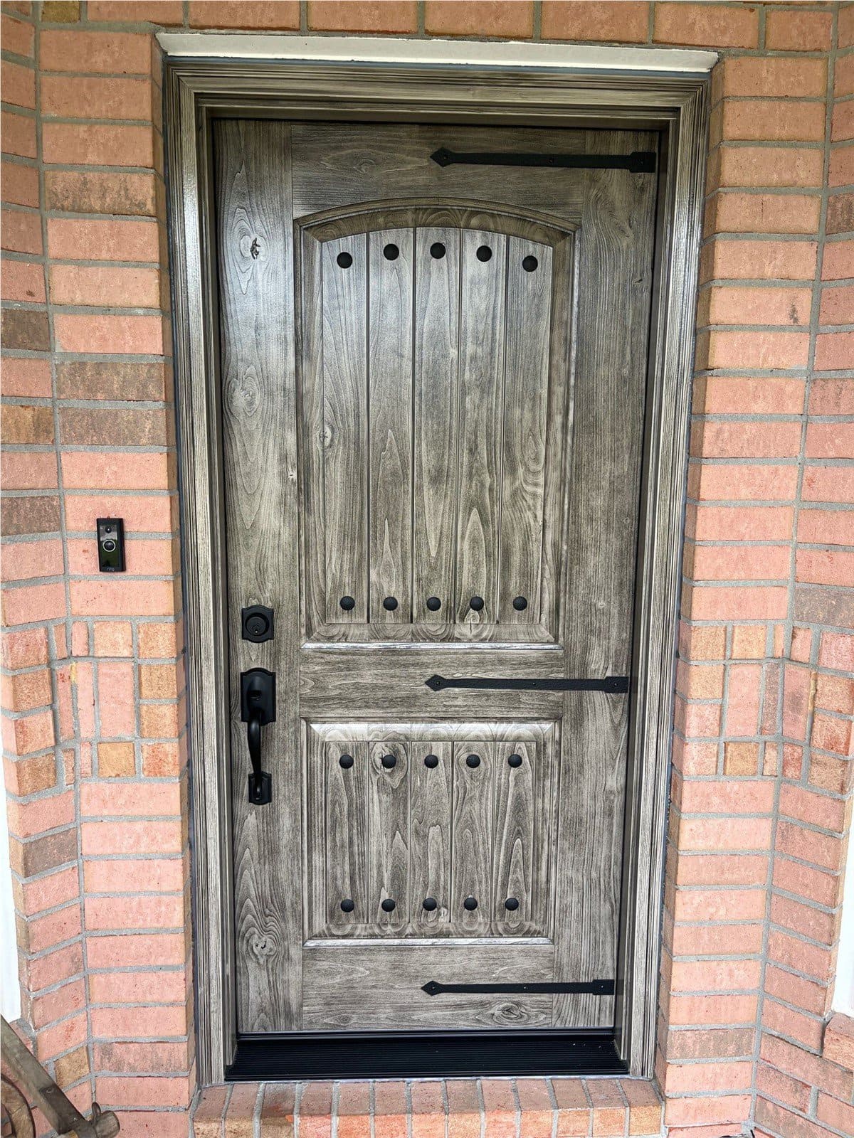 New wood grain front entry door with black hardware and aesthetics, installed by Hometown Contractors, Inc.