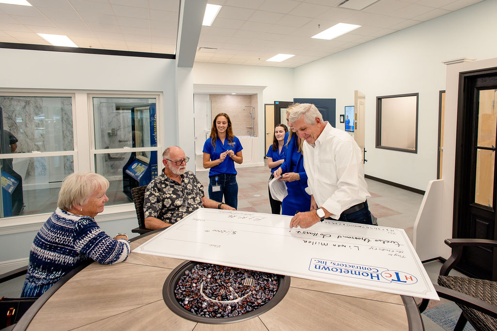 Hometown Contractors owner signing giant check for Grand Prize winners