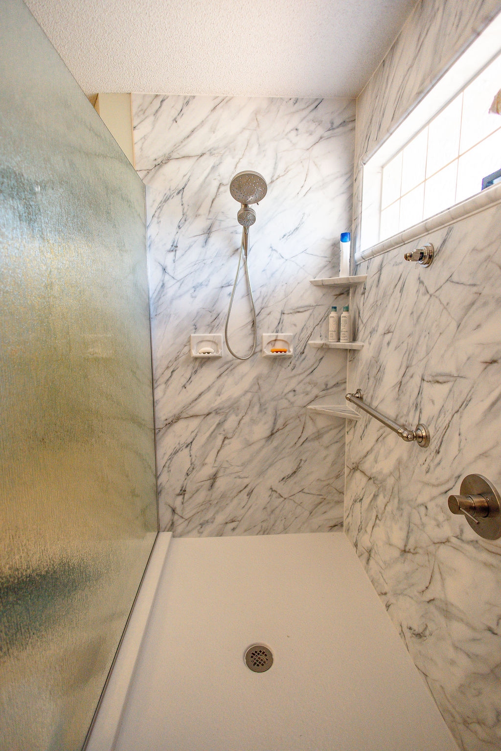 LatashaCarrawayPhotographyOrrell-8007 walk-in shower with detachable wand, grab bar, corner shelving, and opaque barrier