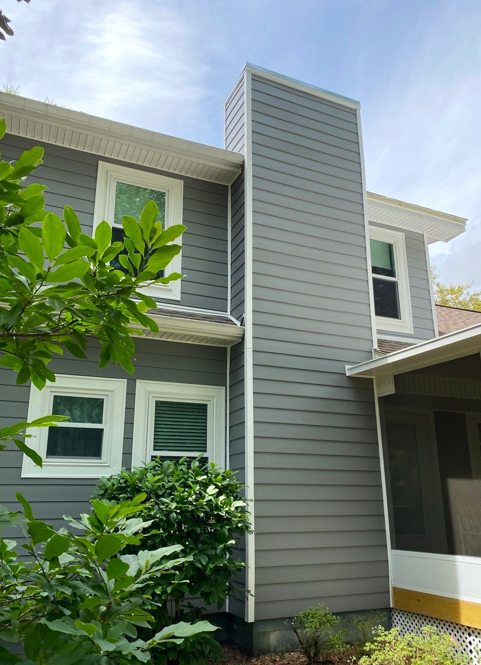 Gallery Gray Siding Gray composite siding on the side of a home with four white trimmed windows and white soffits