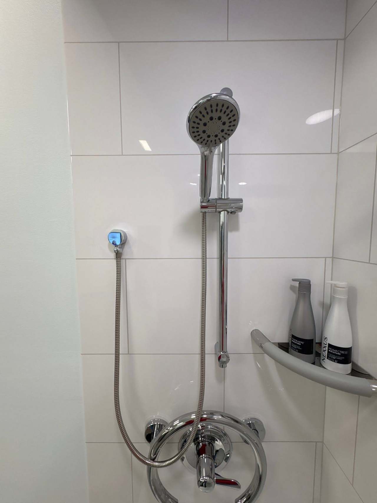 Gallery Shower Details Up close angle of white shower with large gray block pattern and silver hardware with a valve grab bar