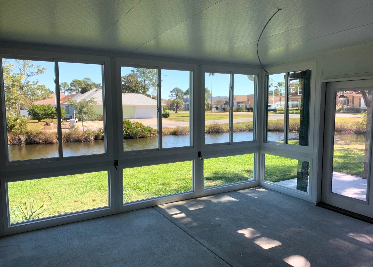 Gallery White Sunroom Inside Inside view of a white sunroom with a view of a backyard and small creek.