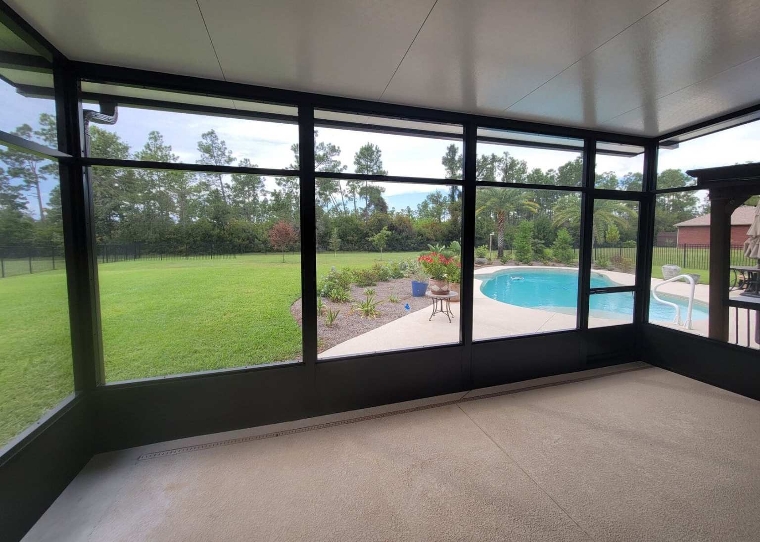 Gallery Black Screen Room Inside Black trimmed screen room from the inside with a view of a backyard and pool
