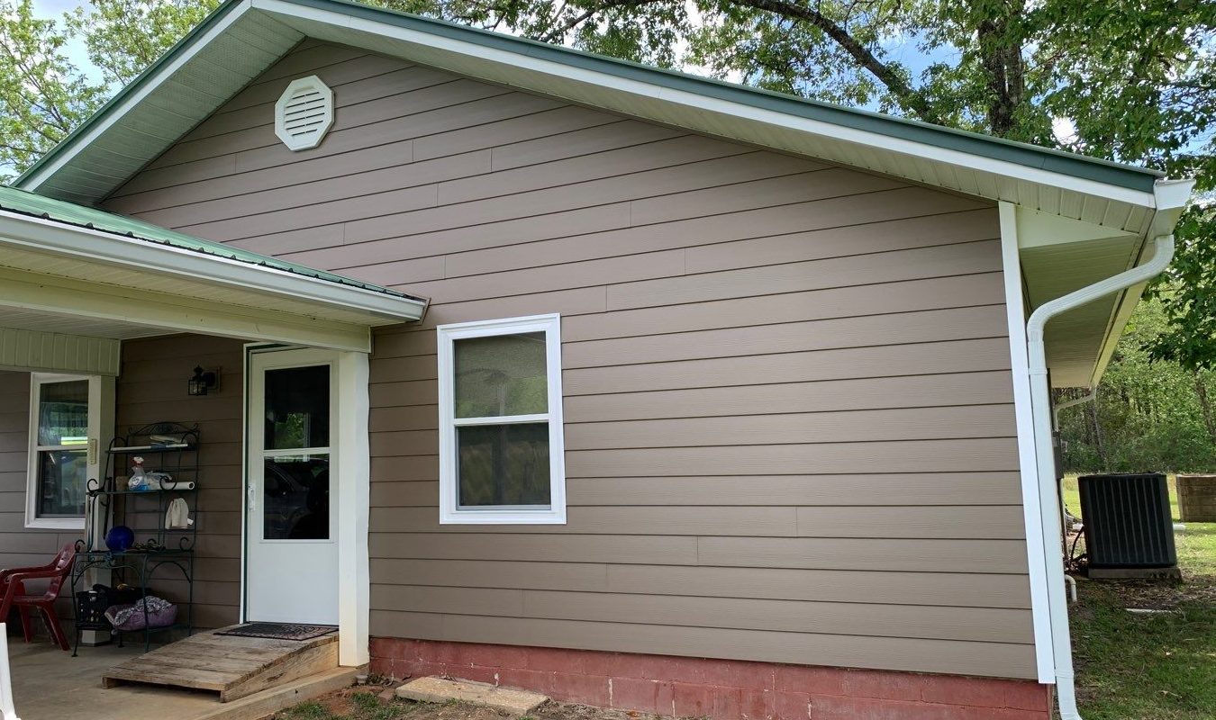 Gallery Canyon Drift Siding1 Light brown composite siding with two white-trimmed windows and a white door beneath a patio cover