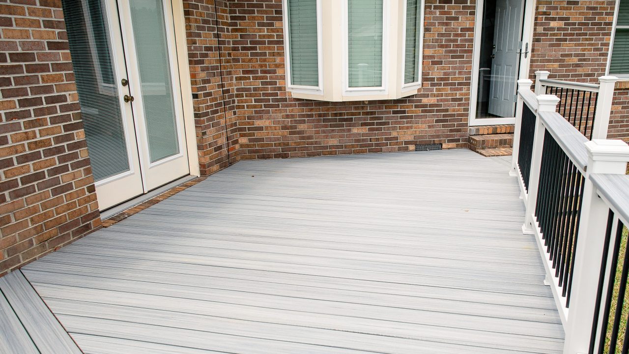 Gray Composite Deck with Black & White Railing 2 Gray composite deck with black and white railings and brick home with French doors and a set of three windows