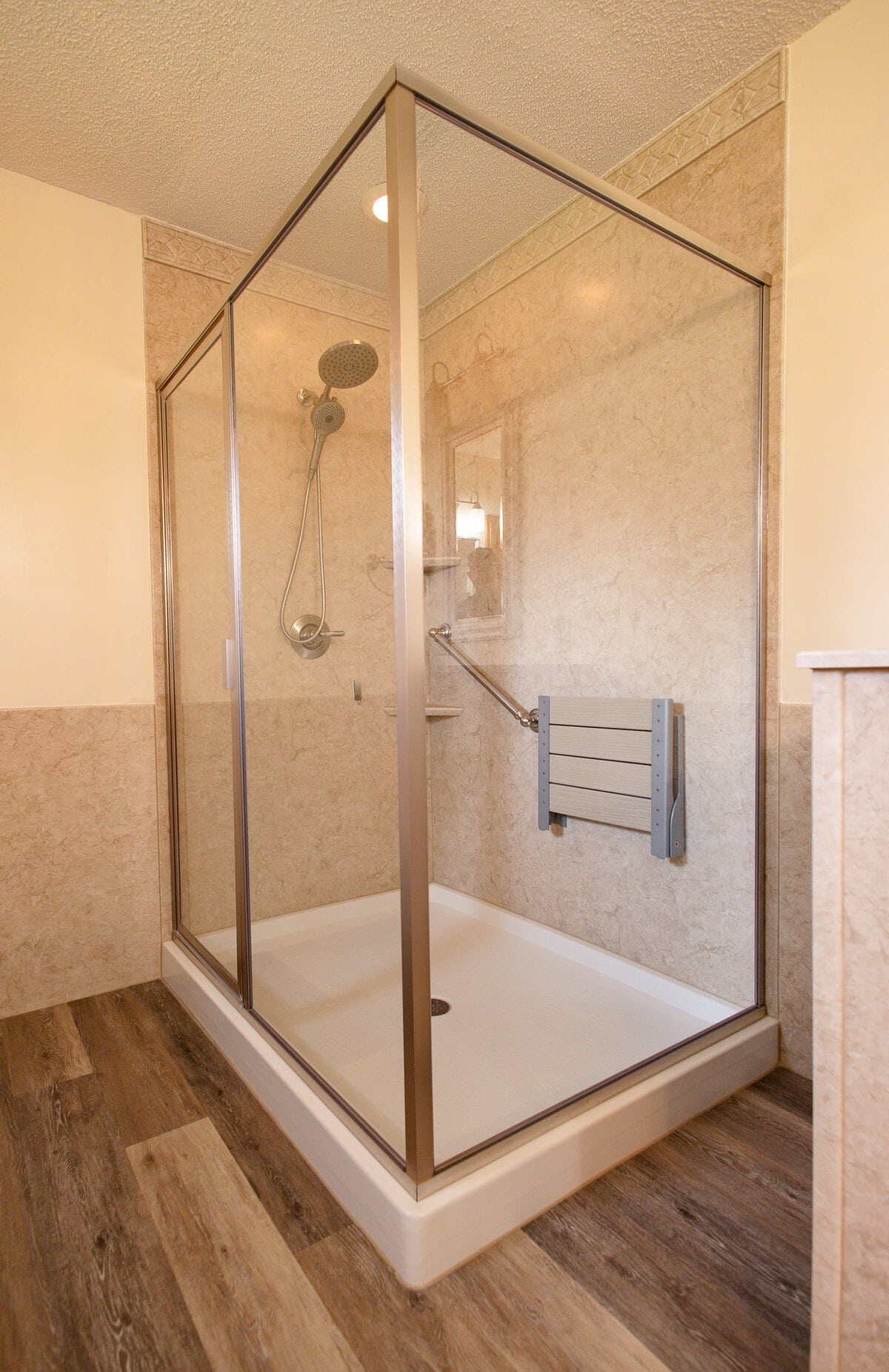 Gallery Shower with Beige Walls Glass-enclosed shower in the corner with beige wall surrounds and beige fold-down seat