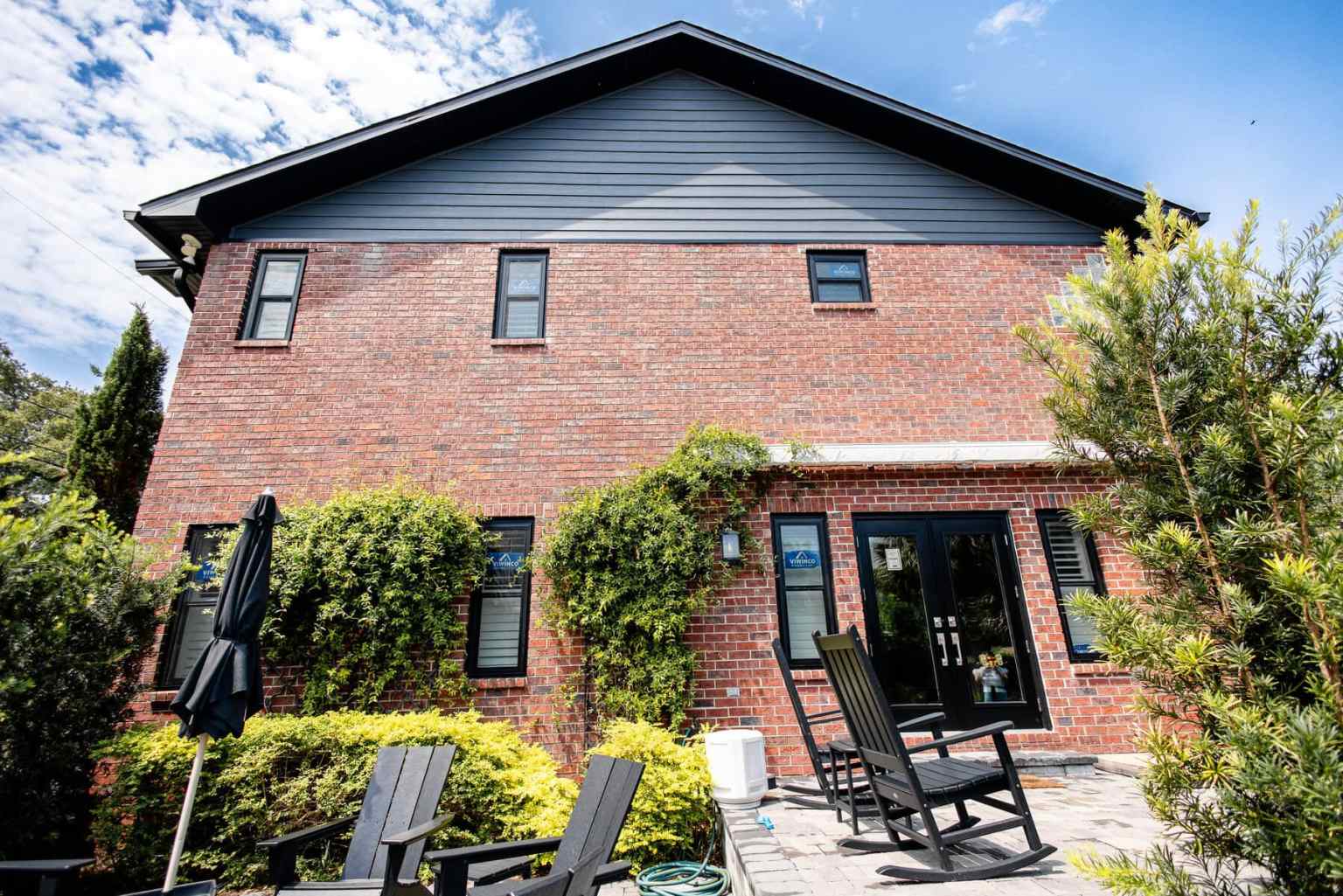 Black Siding on Red Brick Home Black composite siding beneath the black soffits of a red brick home from the back patio