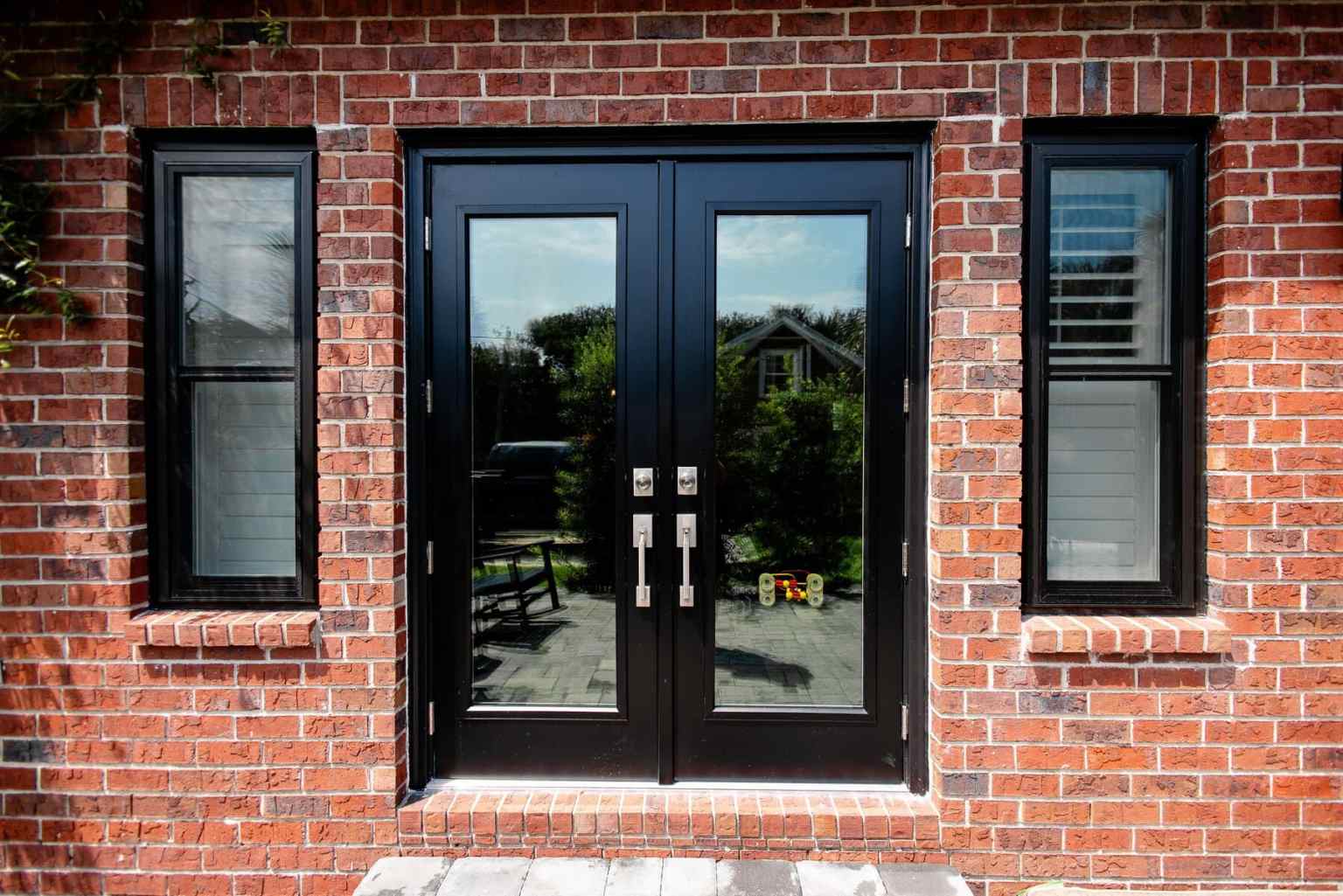 Black Patio Doors Two black-trimmed windows on either side of black patio doors with full windows on each door