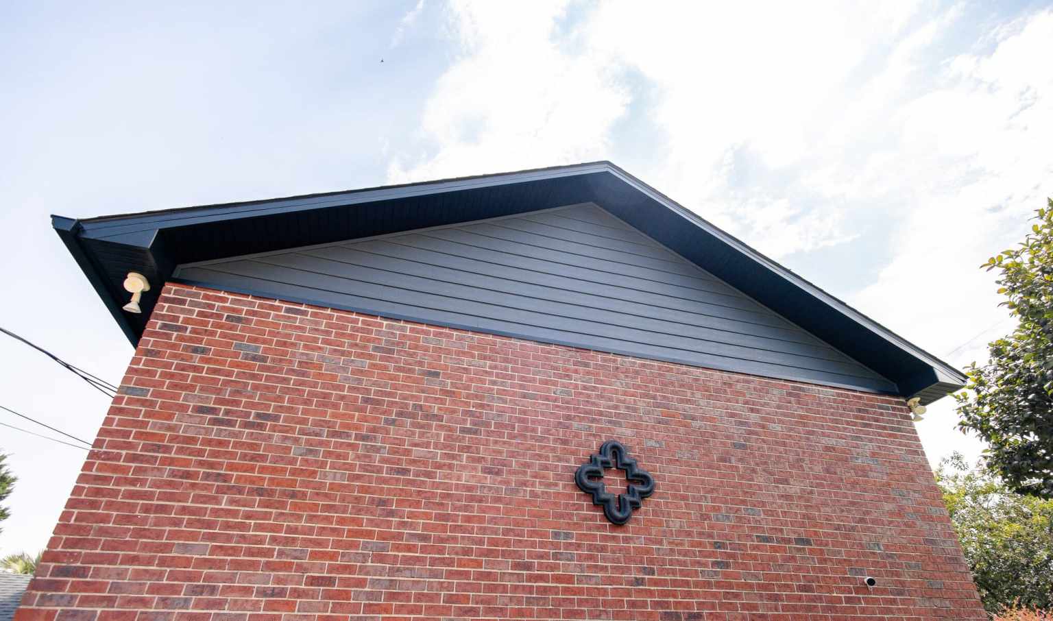 Black Composite Siding Black composite siding beneath black soffits on a red brick home