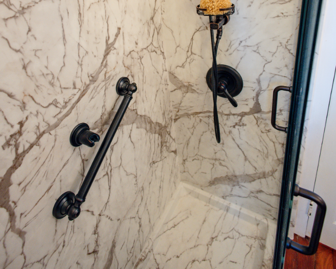 Black grab bar attached to beige and white marbled walls