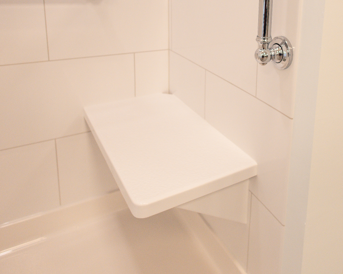 White bench seat in shower with a silver grab bar to the side