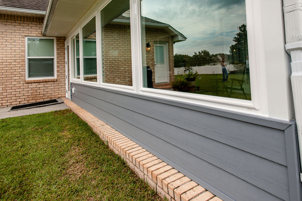 LatashaCarrawayPhotographyH.-9085 detailed angled shot of gray hardy board and picture windows in a porch enclosure attached to red brick home.