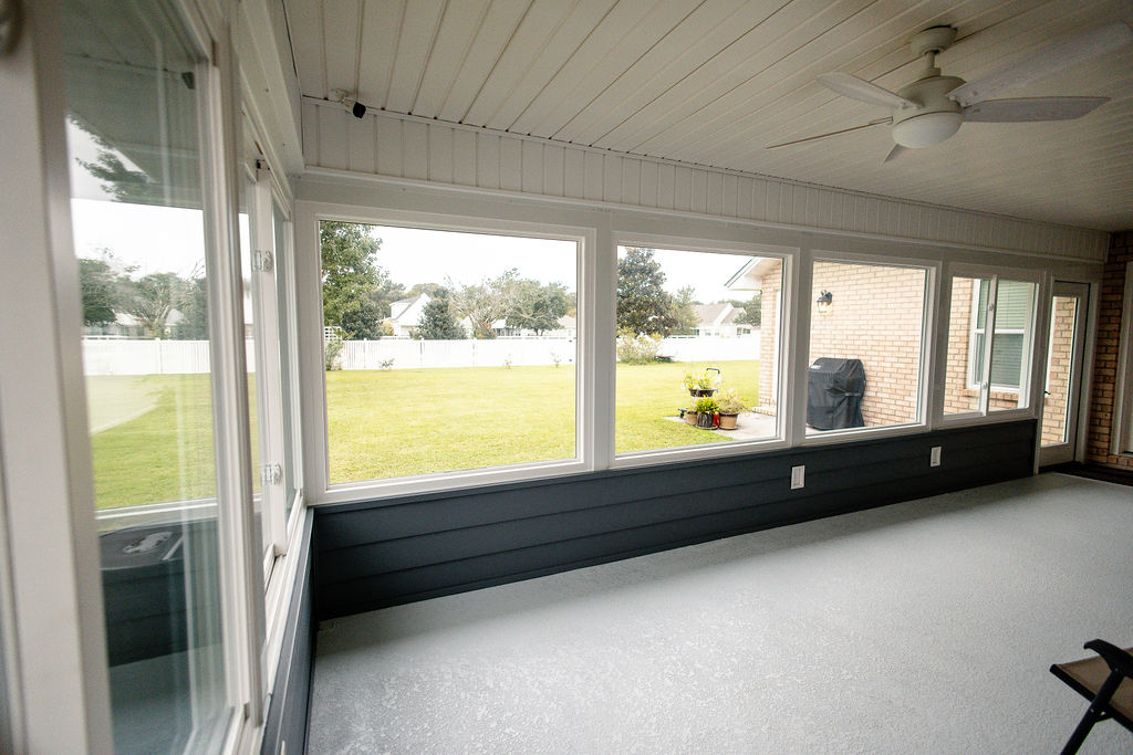 LatashaCarrawayPhotographyH.-9113 Porch enclosure with picture and sliding windows, gray carpet and white ceiling, looking out on backyard.